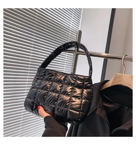 Detail of a black quilted tote bag with puffer style fabric and padded handles