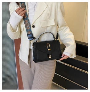 Detail of black crossbody bag with gold U-buckle and retro ethnic print woven strap
