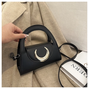 Detail of black trapezoid handbag with silver crescent moon buckle and coin charm pendant