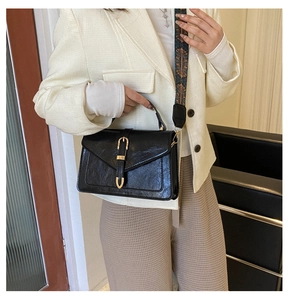 Detail of vintage black crossbody bag with wide ethnic pattern jacquard strap and gold buckle