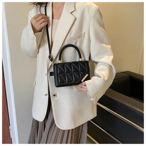 Detail of a black quilted crossbody bag featuring a woven handle and gold hardware