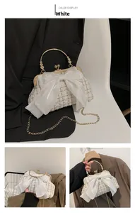 Detail of white tweed handbag featuring a large organza bow and golden metal chain strap