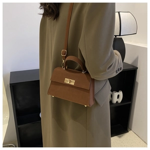 Borsa a tracolla marrone vintage con manico e fibbia dorata su un blazer verde oliva