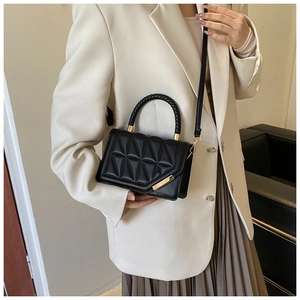 Detailed view of black quilted leather handbag with woven handle and gold hardware