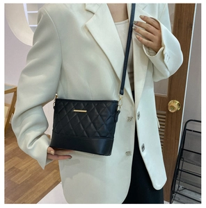 Detail of black quilted leather hobo bag with gold metal trim and crossbody strap