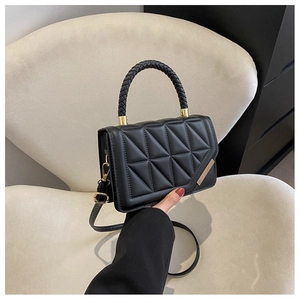 Detail of black quilted leather texture and woven top handle with golden accents