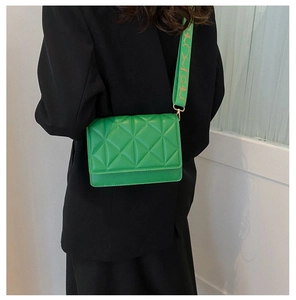 Detail of green quilted PU leather crossbody bag with patterned wide shoulder strap