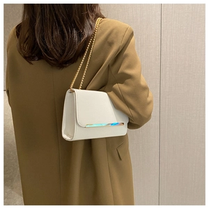 Detalle de bolso bandolera blanco con barra metálica iridiscente y cadena dorada elegante