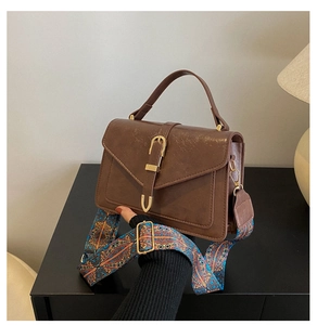 Detail of dark brown retro handbag featuring a colorful ethnic patterned wide strap