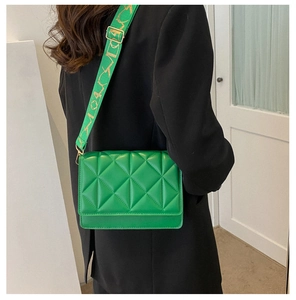 Detail of bright green quilted crossbody bag with decorative jacquard wide strap