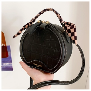 Detail of round black handbag with crocodile texture, contrast stitching and silk scarf