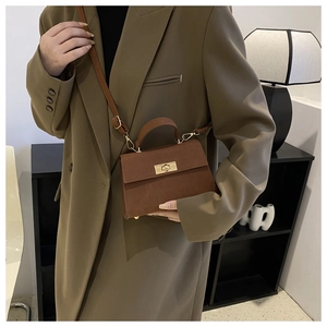 Close-up of brown crocodile embossed leather small square bag with golden turn-lock