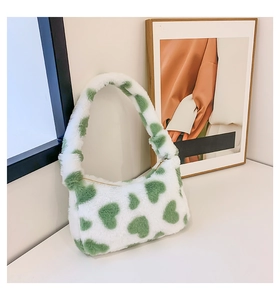 Close-up of white plush crescent bag with green heart pattern and furry texture detail