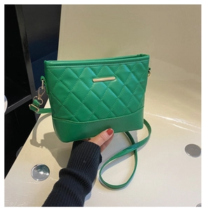 Detail of green quilted leather crossbody bag with elegant gold metal hardware bar