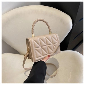 Detail of beige quilted crossbody bag with woven handle and gold metal hardware accents