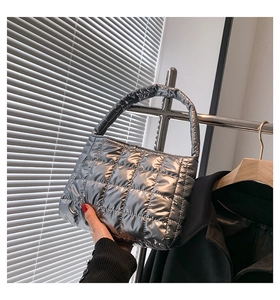 Close-up of quilted silver tote bag with metallic finish and padded puffy square pattern
