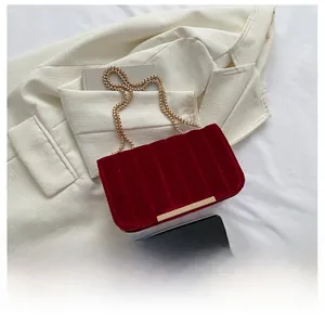 Detail view of red velvet crossbody bag with vertical ribbing and gold chain strap