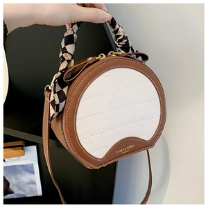 Detail of round crossbody bag with contrast crocodile pattern and silk scarf handle