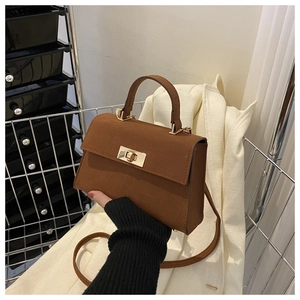 Detail of caramel brown croc-embossed handbag with elegant golden square clasp and handle