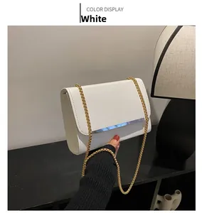 Détail d'un sac à bandoulière blanc avec barre en argent et chaîne dorée fine