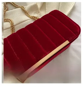 Close-up of burgundy velvet crossbody bag featuring golden chain and vertical quilting