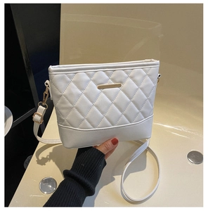 Detailed view of white quilted crossbody bag featuring classic diamond stitching and gold hardware