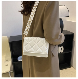 Rear view of a white quilted crossbody bag with a stylish wide embroidered strap on model