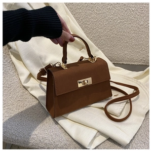 Detail of vintage brown suede crossbody bag with elegant golden twist-lock fastener