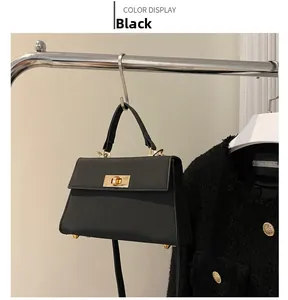 Dettaglio borsa a mano in pelle nera con chiusura dorata e supporto metallico
