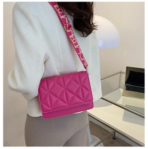 Detail of fuchsia quilted crossbody bag with stylish patterned woven shoulder strap