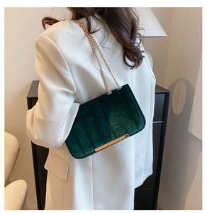 Close-up of emerald green velvet chain bag with vertical quilting and gold metal accents