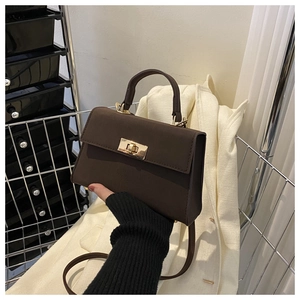 Detailed view of dark brown crossbody bag with gold square twist lock and fine texture