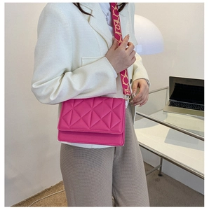 Close-up of rose pink quilted small square bag with decorative wide printed strap