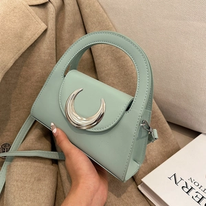 Mint green PU leather crossbody bag with silver moon buckle shown against a coat
