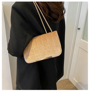 Détail d'un petit sac carré en velours doré avec texture verticale et chaîne