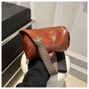 Detail of vintage brown cylinder Boston bag with colorful wide woven shoulder strap