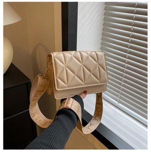 Detail of beige quilted square crossbody bag featuring wide jacquard shoulder strap