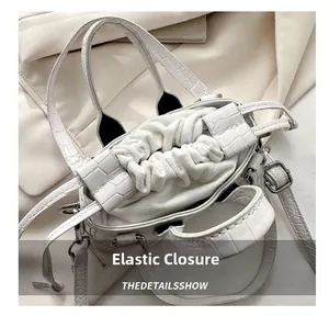 Macro view of beige crocodile embossed handbag with drawstring closure and soft inner lining