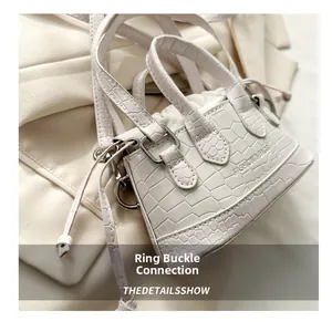 Detail of white crocodile pattern leather handbag with metal buckle and fashion text