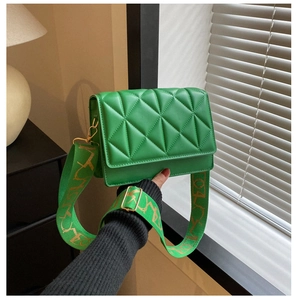Detail of green quilted crossbody bag showing faux leather texture and wide strap