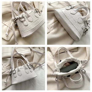 Detail of white crocodile pattern mini bag featuring drawstring closure and side logo engraving