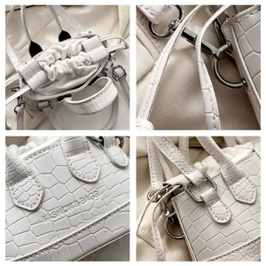 Detail view of white croc-embossed handbag featuring drawstring closure and silver hardware