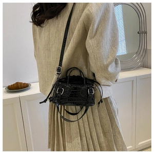 Detail of black crocodile texture mini tote with drawstring liner and silver buckle hardware