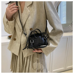 Close-up of black croc-embossed mini crossbody bag with silver hardware and drawstring lining