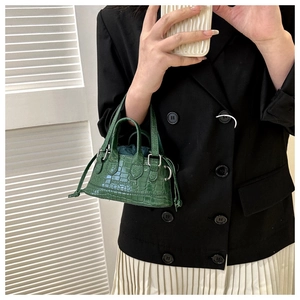 Close-up of a dark green crocodile pattern mini handbag with decorative side drawstrings