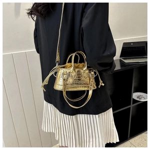 Close-up of a mini gold tote bag with crocodile texture and drawstring lining