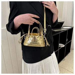 Detailed shot of golden mini crossbody bag with crocodile pattern and drawstring liner