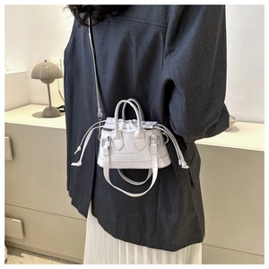 Detailed shot of white crocodile embossed mini crossbody bag worn on a grey blazer