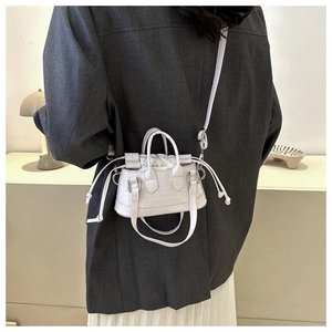 Detail of white crocodile pattern crossbody bag with drawstring closure and silver hardware