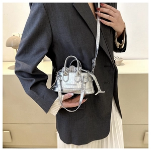 Detail of silver crocodile pattern mini crossbody bag with embossed text and drawstring